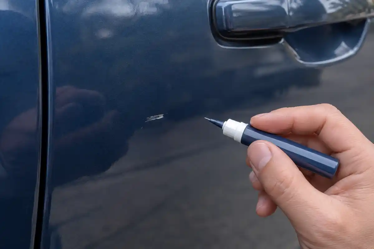 Retouche peinture automobile au stylo pour un petit défaut localisé, sans garantie de résultat invisible ni réparation d’une rayure profonde.